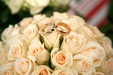 gold wedding rings lie on a bouquet of roses