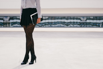 Trendy fashion business woman holding digital tablet outside corporate building. Unrecognizable...