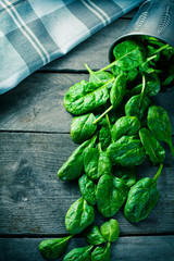 Baby spinach spilled with overturned buckets and kitchen towel on wooden board. © cegli