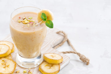 banana milkshake in a glass on white wooden board