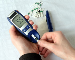 Checking blood glucose level with a glucose meter with blood drop