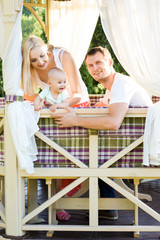 Obraz premium Happy young family spending time outdoors on a summer day with blue sky in background. Spending time together having fun and smiling. Parents and their child. 