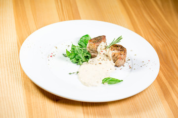 Beautiful juicy grilled meat with garnish on a wooden table