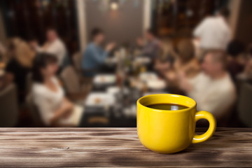 Coffee in cup on wooden table opposite a blurred background