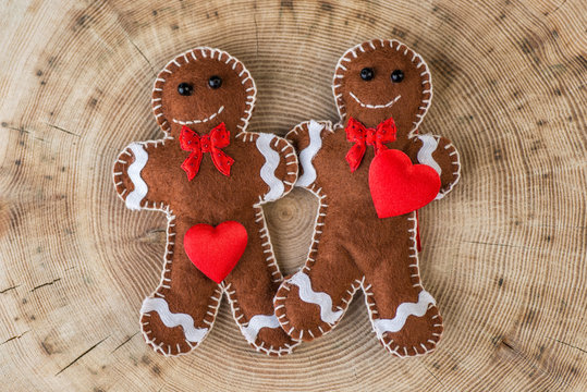 two fabric gingerbread on wooden background with hearts, funny picture for valentines day, love story