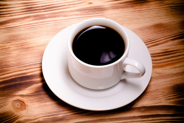Coffee in cup on light wooden table. Toned
