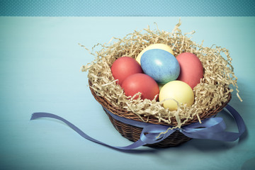 Easter eggs in a nest on blue background. Toned