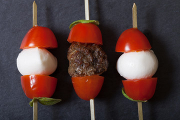 Small snacks canape with cherry tomatoes, mozzarella and meatbol