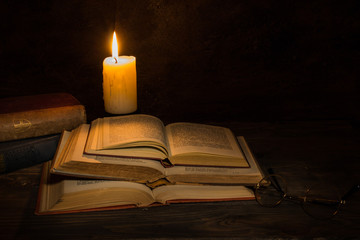 old books being read by candle light