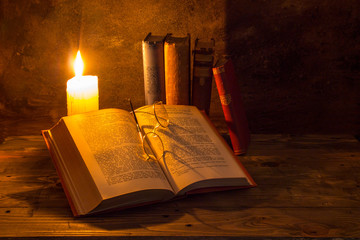 old books being read by candle light