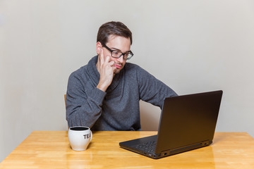 Mann arbeitet im Sitzen an einem Laptop