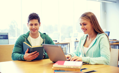 happy students with laptop and books at library