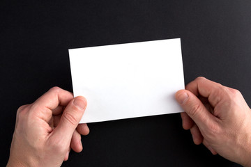 Men's hands holding a white blank sheet of paper