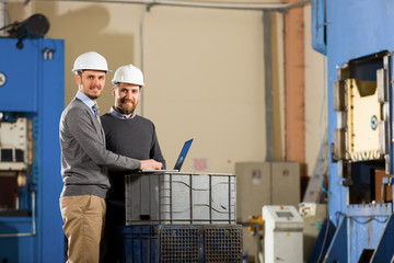 Two businessman working with laptop in factory