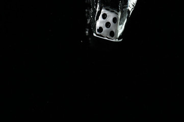 Dice falling into water. On a black background.