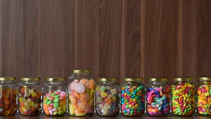Gartenposter Süßigkeiten Various colorful sugary candy in a class jar