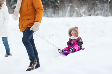 happy family with sled walking in winter forest