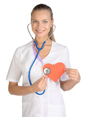 Woman cardiologist listens paper heart in hand