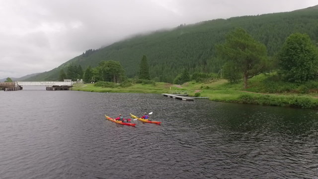 Aerial shot of 2 kayaks going down a river in the Scottish highlands 

