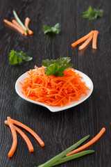 Carrot on a white plate on a wood background.