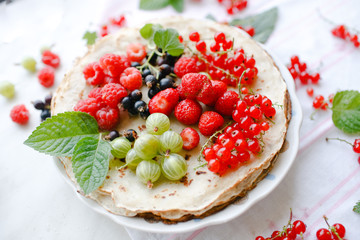 Traditional thin russian pancakes with season berries and mint