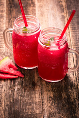Fresh watermelon smoothie drink in mason jar on black stone.