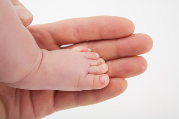 Children's foot on a background of her mother's arms.