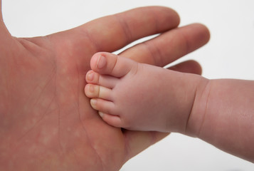 Children's foot on a background of her mother's arms.