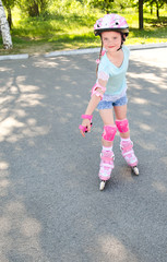 Fototapeta premium Cute smiling little girl in pink roller skates
