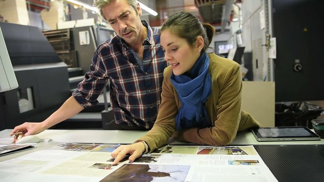 Man in printing house showing client proof documents
