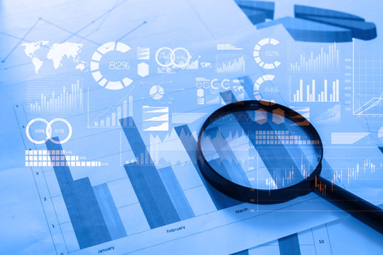 Magnifying glass and documents with analytics data lying on tabl