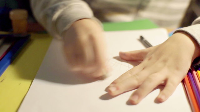 Child painting something and using rubber to wipe it from the paper

