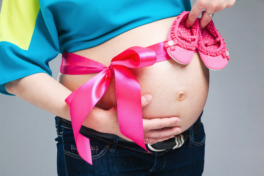 Pregnant belly with pink ribbon.