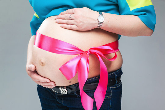Pregnant belly with pink ribbon.
