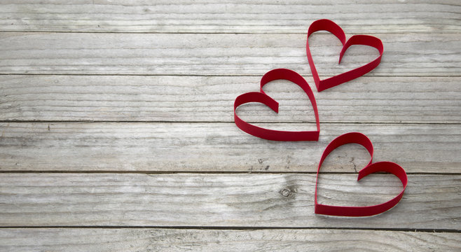 Three red hearts on a wood background