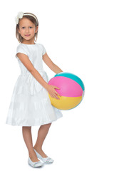 Cute little girl in fancy white dress holding a big striped beach ball - Isolated on white background