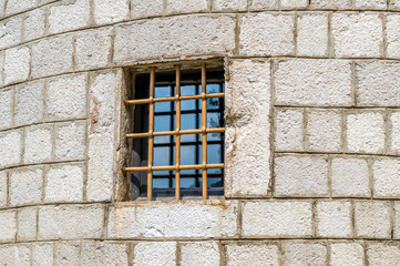 Fototapeta na wymiar Fortress wall with a window protected by iron rod. Ostrog monastery chapel. Niksic, Montenegro