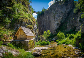 Nevidio canyon. Rock cliff, river, bridge and small wooden house.  Invisible canyon, popular touristic attraction of Montenegro.