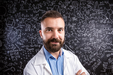 Teacher in white coat against big blackboard with mathematical s