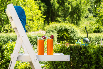 Two glasses of orange juice and strawberries in the summer garde