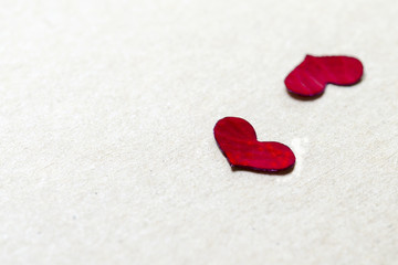 Red petal in heart shape on brown paper background