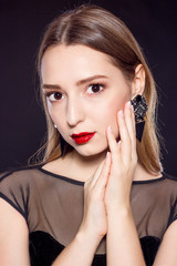 Portrait of a beautiful young woman on a black background. Beautiful woman with red lips in black dress.