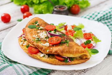 Omelet with tomatoes, parsley and feta cheese on white plate.