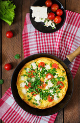 Omelet with tomatoes, parsley and feta cheese in pan. Top view