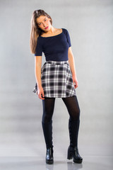 Smiling  girl standing on the gray background. Positive emotional little girl with long healthy hair and a sweet smile posing at the camera on a gray background