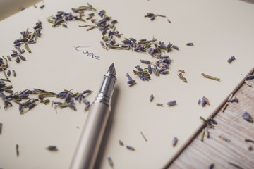 Word love written with a fountain pen in the heart of lavender