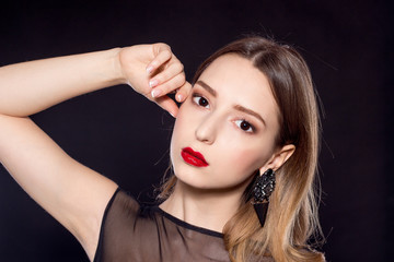 Portrait of a beautiful young woman on a black background. Beautiful woman with red lips in black dress.