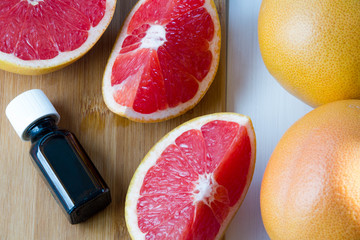Essential oil in glass bottle with fresh, juicy grapefruit. Spa concept.