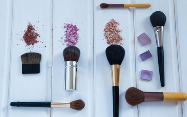 women's accessories cosmetics. Makeup brushes and crushed eyeshadow on wooden background