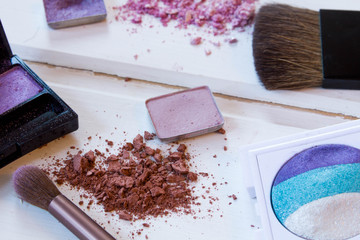 women's accessories cosmetics. Makeup brushes and crushed eyeshadow on wooden background